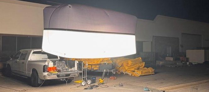 Lighting balloon glowing above a pickup truck during an overnight production setup