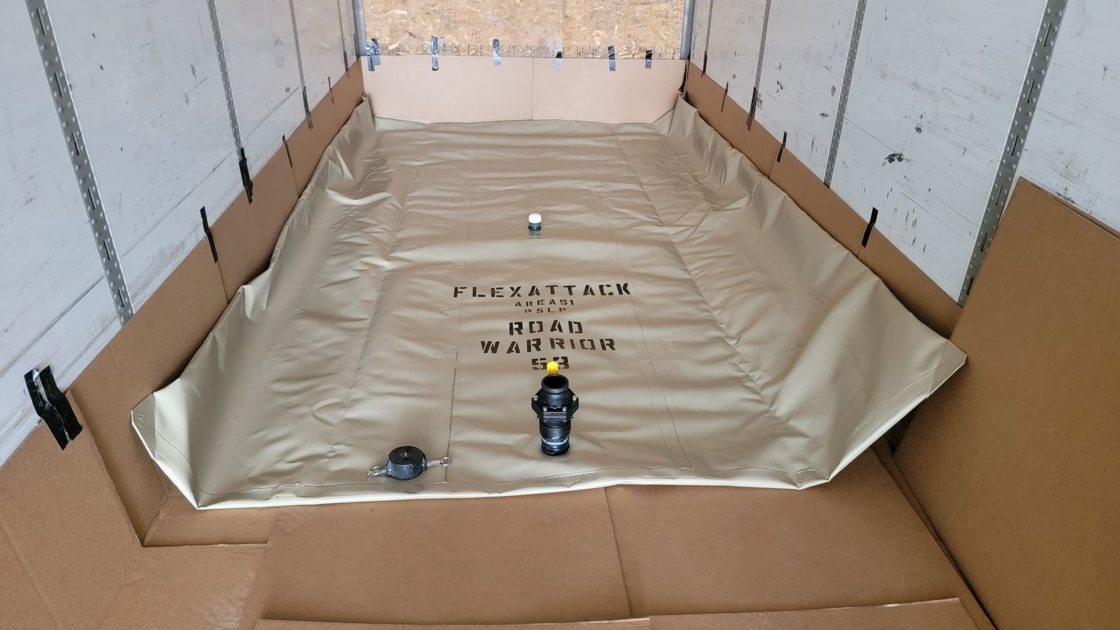 Empty transport flexitank laid flat across the lined floor of a box trailer before filling