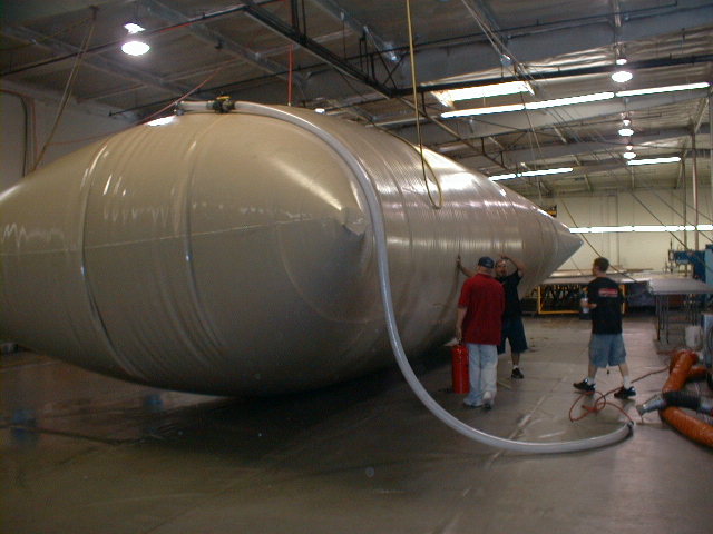 Shop crew filling a long-format custom vessel tank through a discharge hose