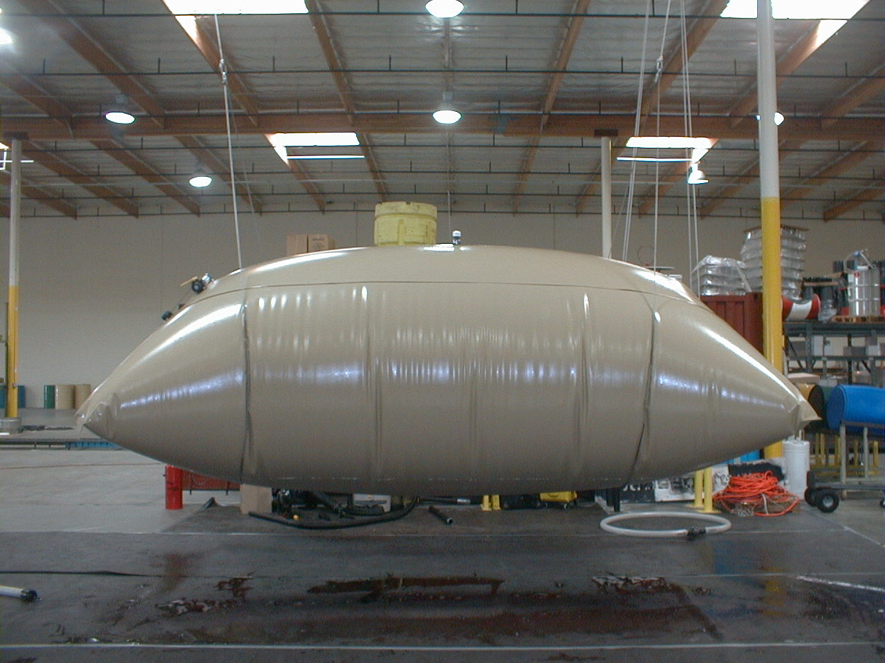 Side elevation of a filled custom fuel bladder suspended for inspection in the fabrication shop